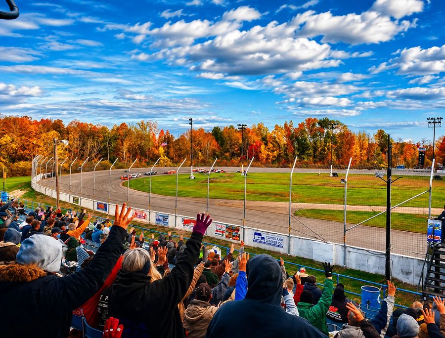 Fans with arms raised in the stands on an autumn race day