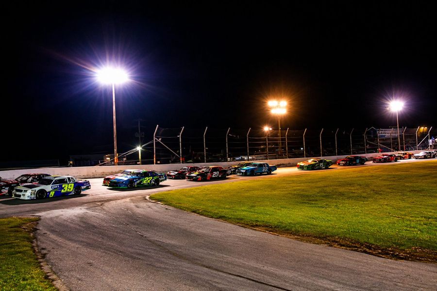 Stock cars racing under the lights at night