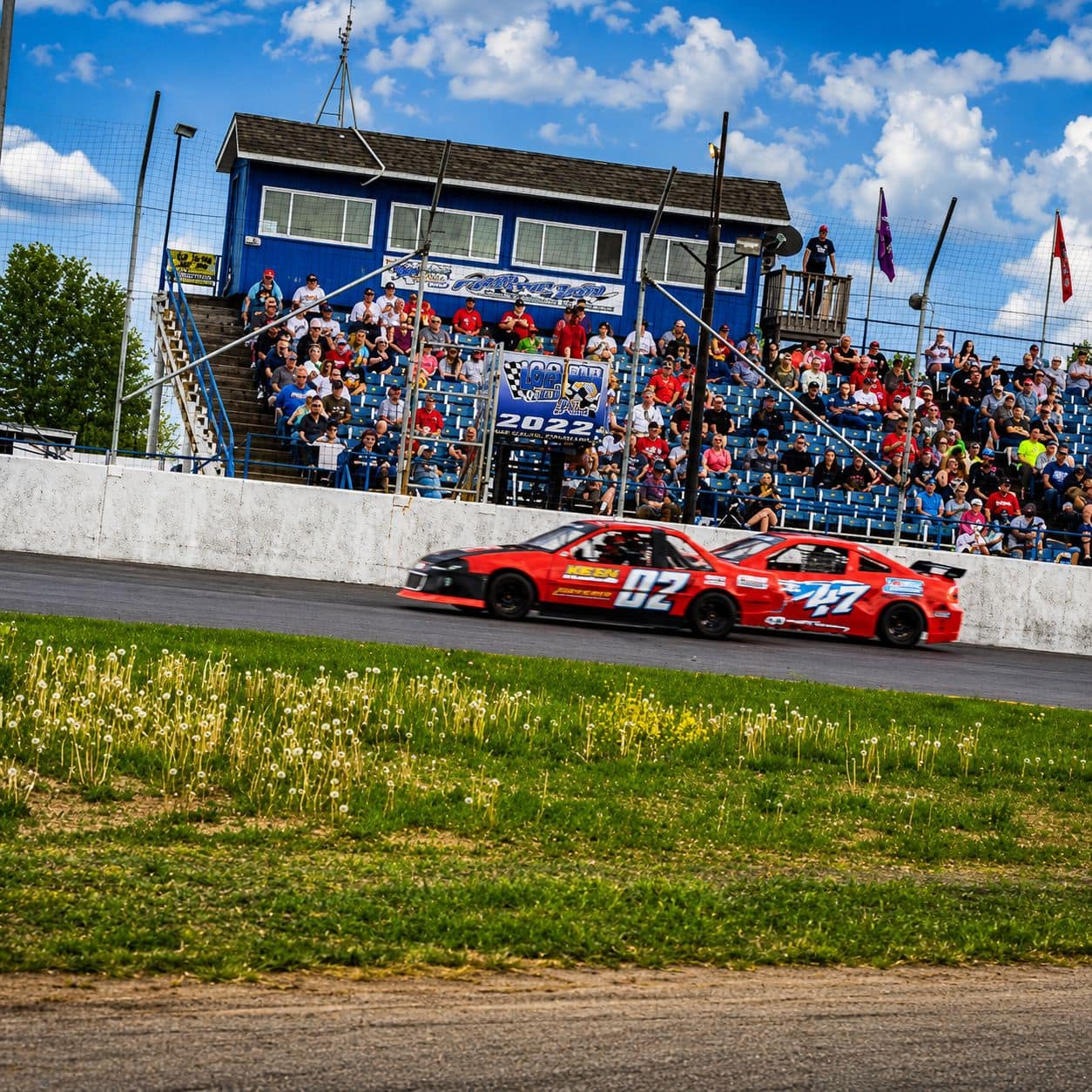 Fans in the grandstand as cars pass on the front stretch